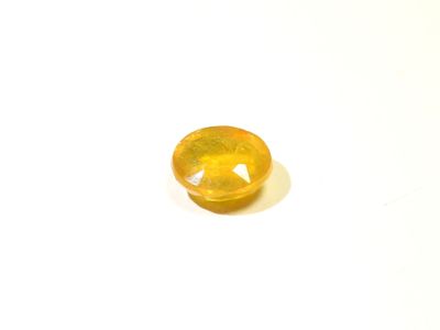 a close up of a yellow gemstone on a white surface
