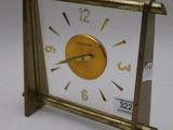 a small gold clock with a white face on a table