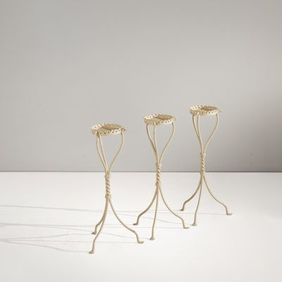 trois supports métalliques pour plantes posés sur une surface blanche, avec un fond blanc