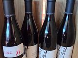 four bottles of wine are lined up on a shelf