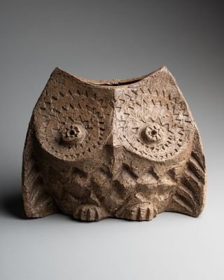 une image représentant un vase en pierre sur le dessus duquel est représenté un hibou