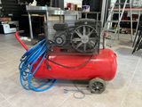 a red air compressor sitting on the floor in a room