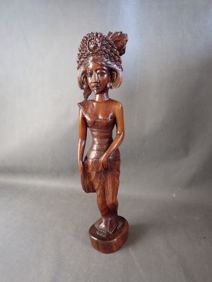 statue en bois représentant une femme tenant un panier, posée sur un socle