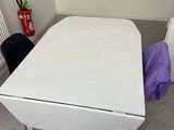 une table blanche sur laquelle est posé un sac violet