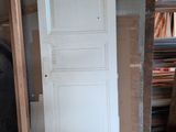 a white door in the middle of a room next to a ladder