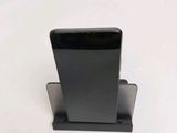a black cell phone on a stand on a white surface