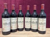six bottles of red wine are lined up on a wooden table