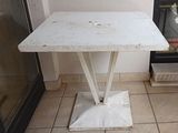 une petite table blanche posée sur un sol carrelé, près d'une fenêtre