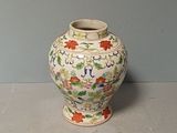 a white vase with flowers on it sitting on a table