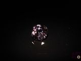 a close up of a purple diamond sitting on top of a black surface