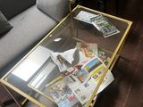 une table basse en verre sur laquelle sont posés des magazines, dans un salon