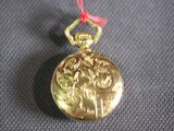 a gold pocket watch with a red string on it