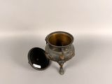 an old silver cup with a black lid sitting on a white surface