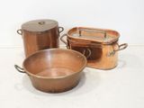 three copper pots and pans sitting on a table