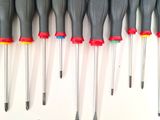 seven screwdrivers lined up in a row on a white surface