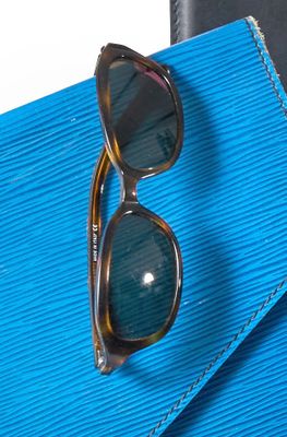 un sac à main bleu sur lequel sont posées une paire de lunettes de soleil