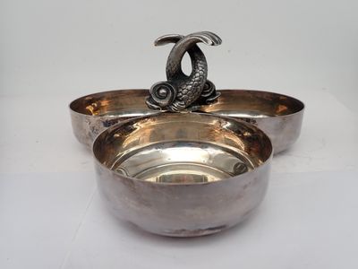 a silver bowl with a fish on top of it