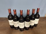 six bottles of wine are lined up on a wooden table