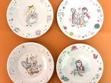 quatre assiettes ornées de personnages de dessins animés, sur un fond orange