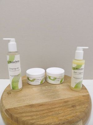 un plateau en bois sur lequel sont posées trois flacons de produits de soin pour la peau
