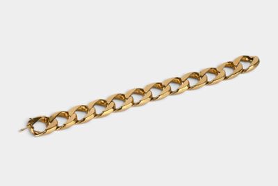 gros plan d'un bracelet en chaîne en or sur fond blanc