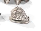trois objets métalliques argentés posés sur une surface blanche, sur fond blanc