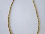 un collier en or représentant une corde torsadée sur fond blanc
