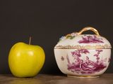 a yellow apple next to a purple and white bowl on a table