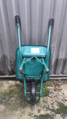 a green wheelbarrow with a sign on the side of it