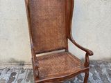 une chaise en bois posée sur un trottoir, près d'un mur