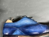 someone is holding a pair of blue shoes on a gray surface