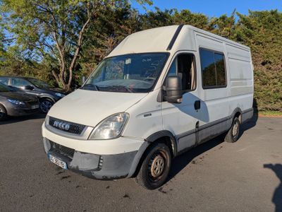 une camionnette blanche garée sur un parking avec des arbres en arrière-plan