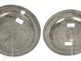 pair of silver plates with labels on them sitting on a stand