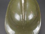 an old green helmet on a black surface with a gray background