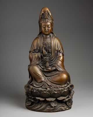 a bronze figure of a buddha sitting on a lotus flower