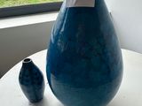 a large blue vase and two small blue vases on a table