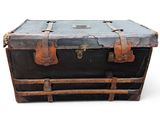 an old black trunk with leather straps on a white background