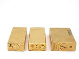 three gold lighters sitting side by side on a white surface