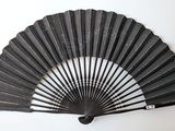 a black fan hanging on the wall next to a white wall