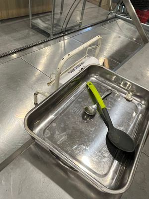 une casserole en métal contenant une spatule, posée sur un plan de travail