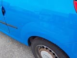 a small blue car parked on the side of the road