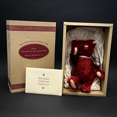 un ours en peluche rouge dans une boîte contenant une carte