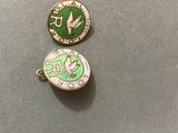 two pins with a green and white design on them sitting on a table
