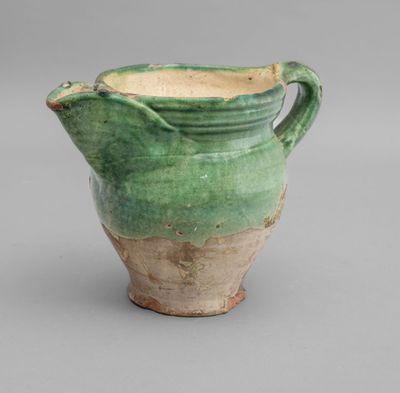 green and white pitcher with handles on a gray surface