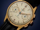 a close up of a gold wrist watch with a black leather strap