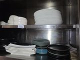 de nombreuses assiettes et bols empilés sur une étagère dans la cuisine