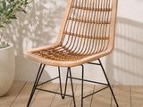 La chaise en rotin est posée sur un parquet, à côté d'une plante en pot.