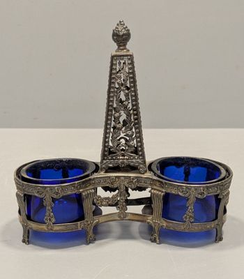 un bougeoir ancien en argent et en verre bleu posé sur une table blanche