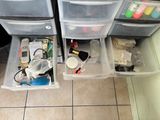 two plastic drawers with various items in them on the floor