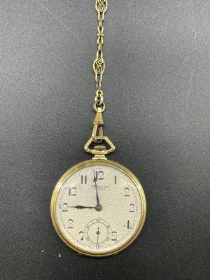 un gros plan d'une montre de poche en or attachée à une chaîne